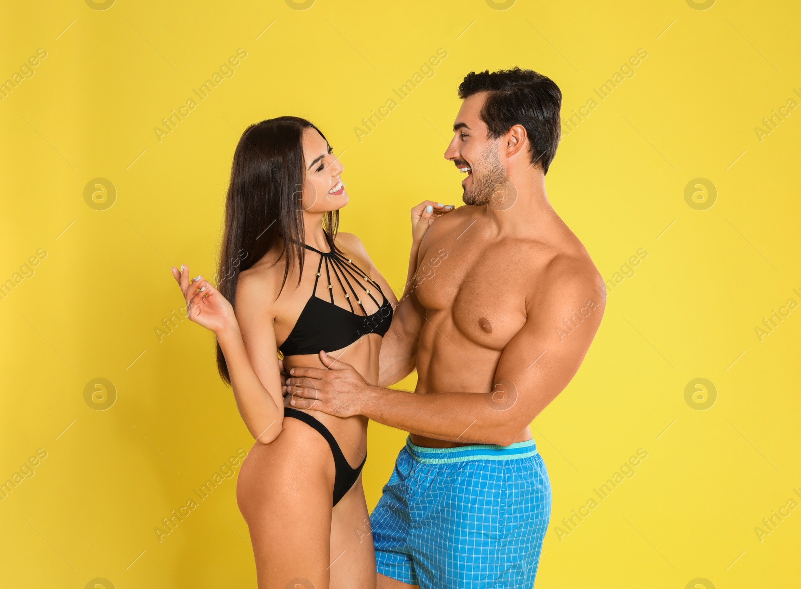 Photo of Young attractive couple in beachwear on yellow background