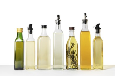 Photo of Bottles of different cooking oils on white background