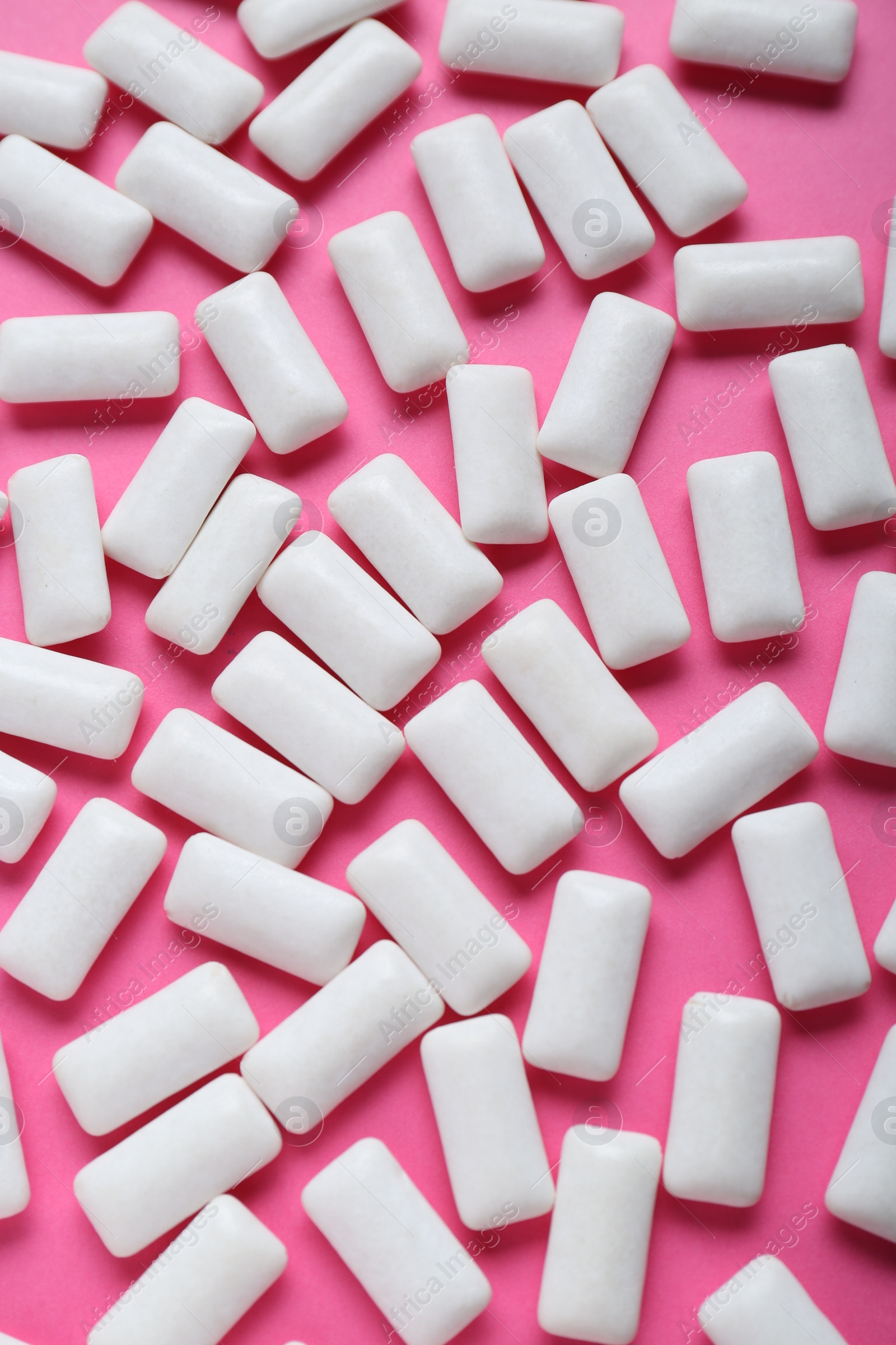 Photo of Tasty white chewing gums on pink background, flat lay