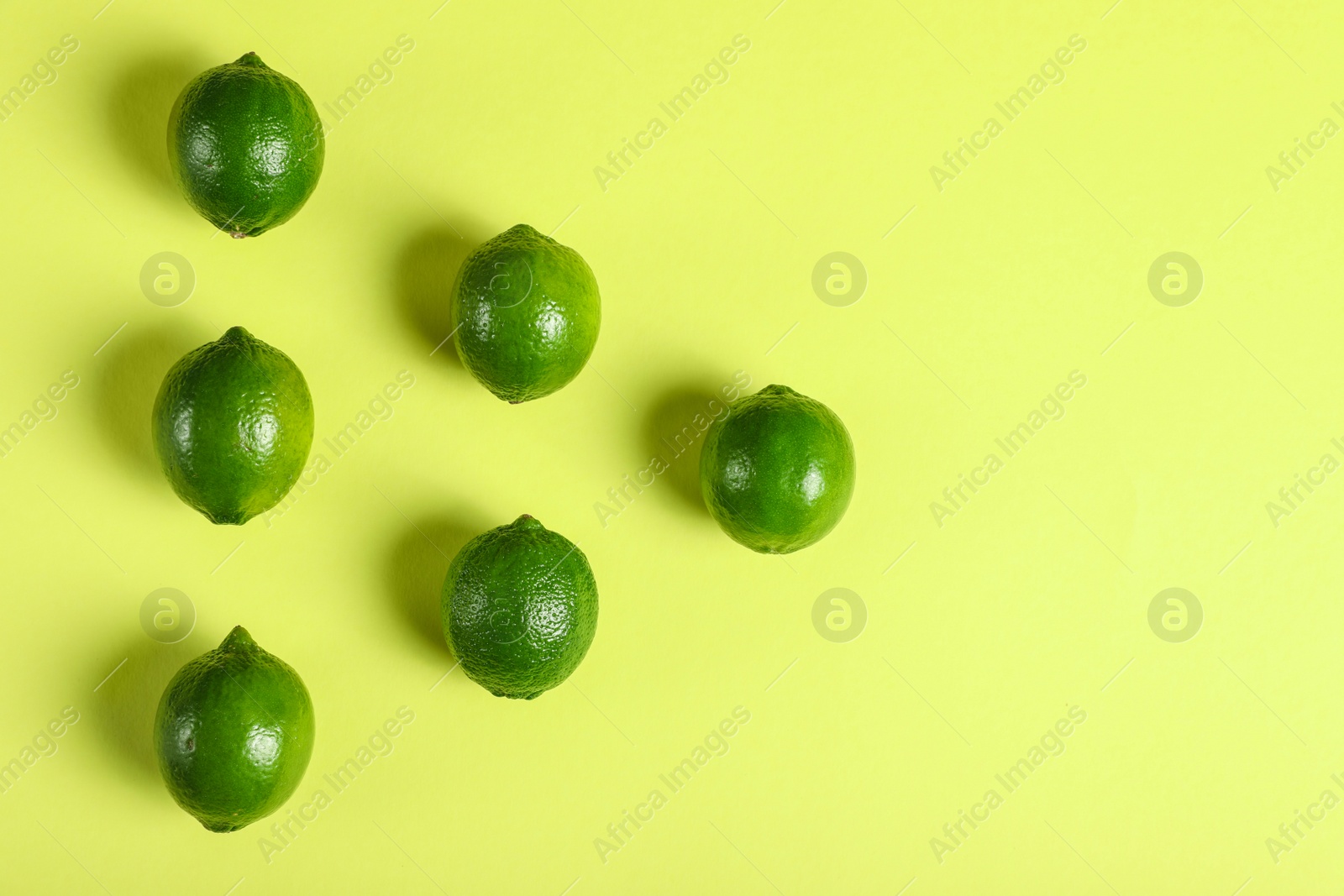 Photo of Flat lay composition with fresh juicy limes on yellow background, space for text