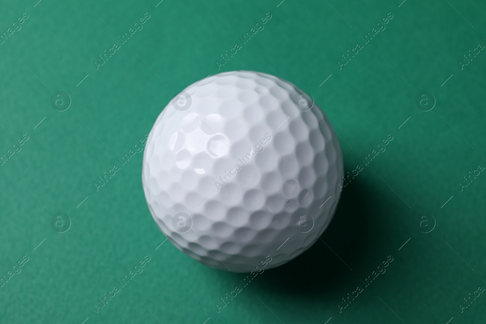 Photo of One golf ball on green background, top view