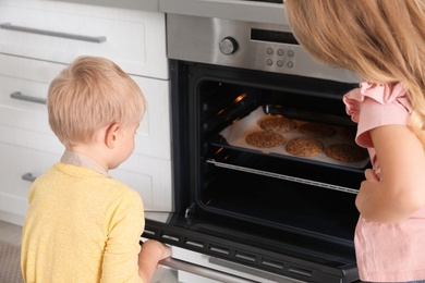 Little kids baking cookies in oven at home