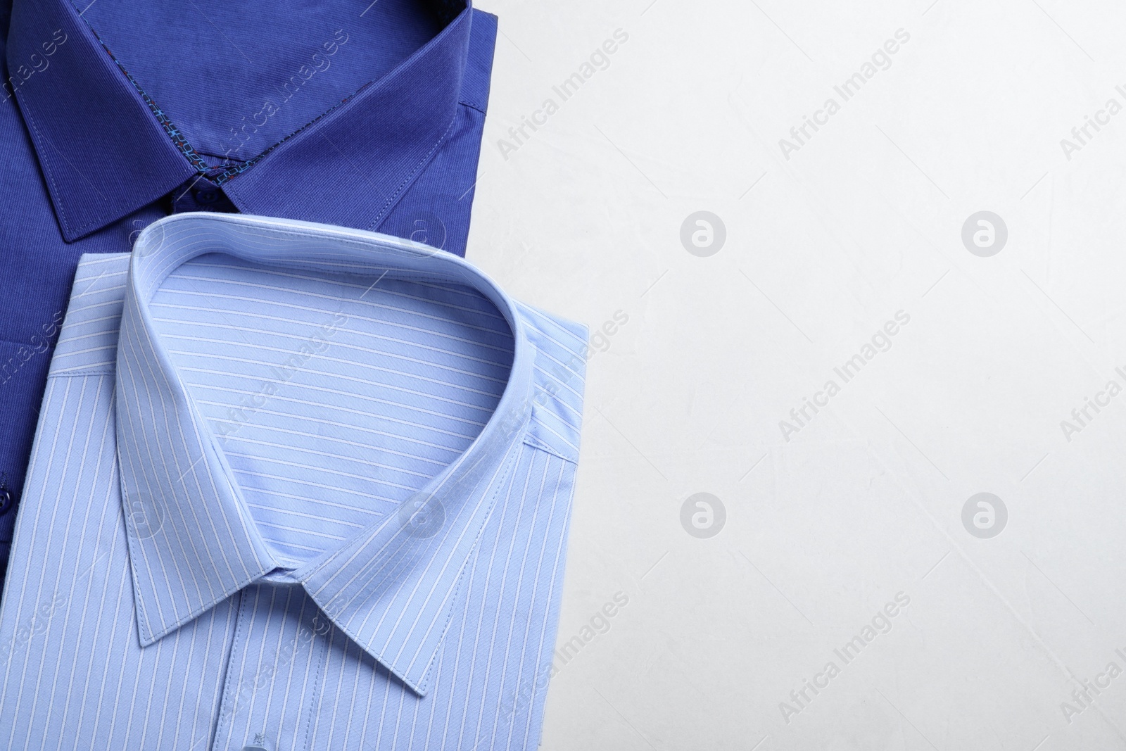 Photo of Stylish shirts on light table, flat lay with space for text. Dry-cleaning service