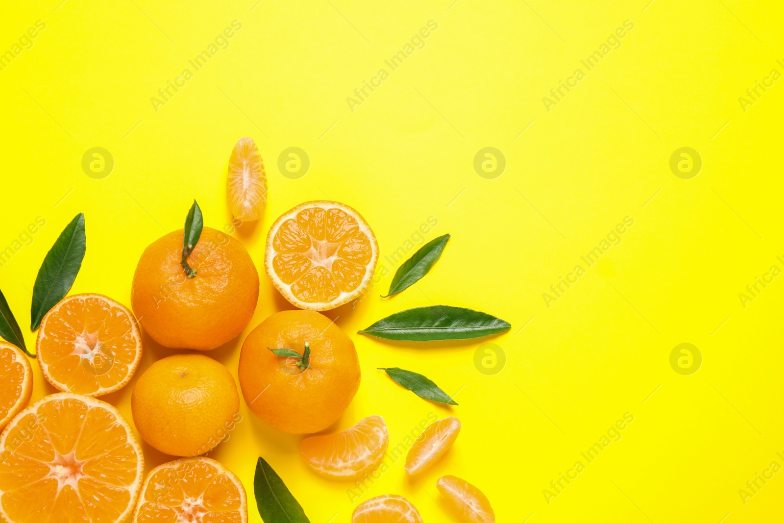 Photo of Flat lay composition with fresh ripe tangerines and leaves on yellow background, space for text. Citrus fruit