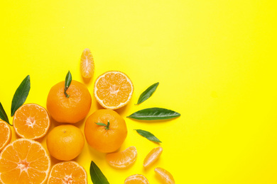 Flat lay composition with fresh ripe tangerines and leaves on yellow background, space for text. Citrus fruit