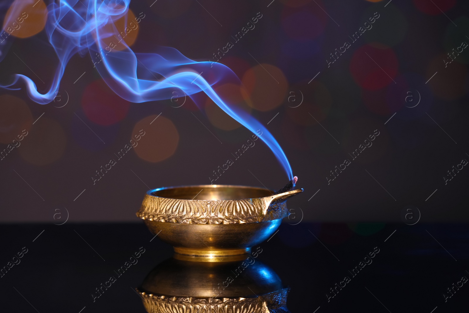 Photo of Blown out diya on dark background with blurred lights. Diwali lamp