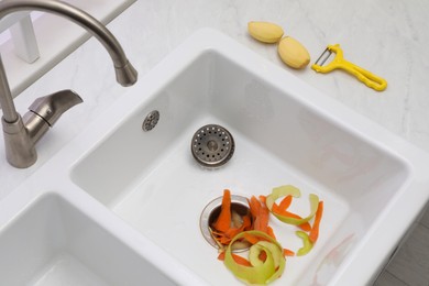 Photo of Vegetable scraps in kitchen sink with garbage disposal, above view