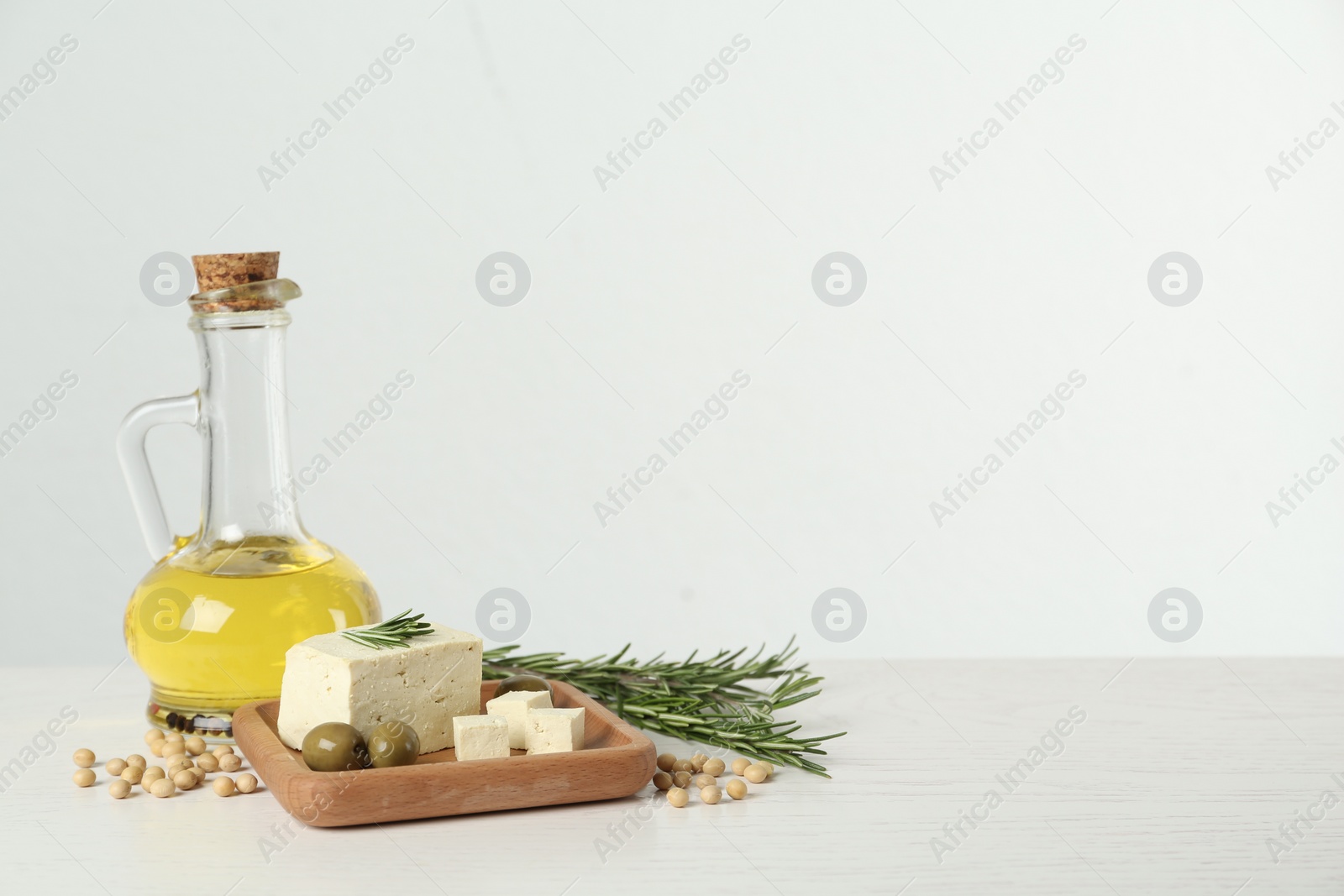 Photo of Pieces of delicious tofu with rosemary, olives and soy on white table, space for text