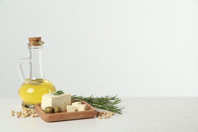 Photo of Pieces of delicious tofu with rosemary, olives and soy on white table, space for text