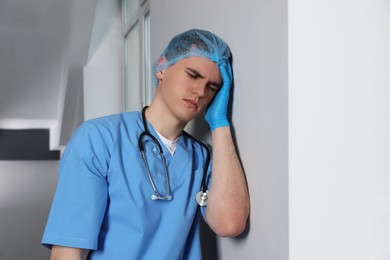 Photo of Stressed doctor near grey wall in hospital hallway