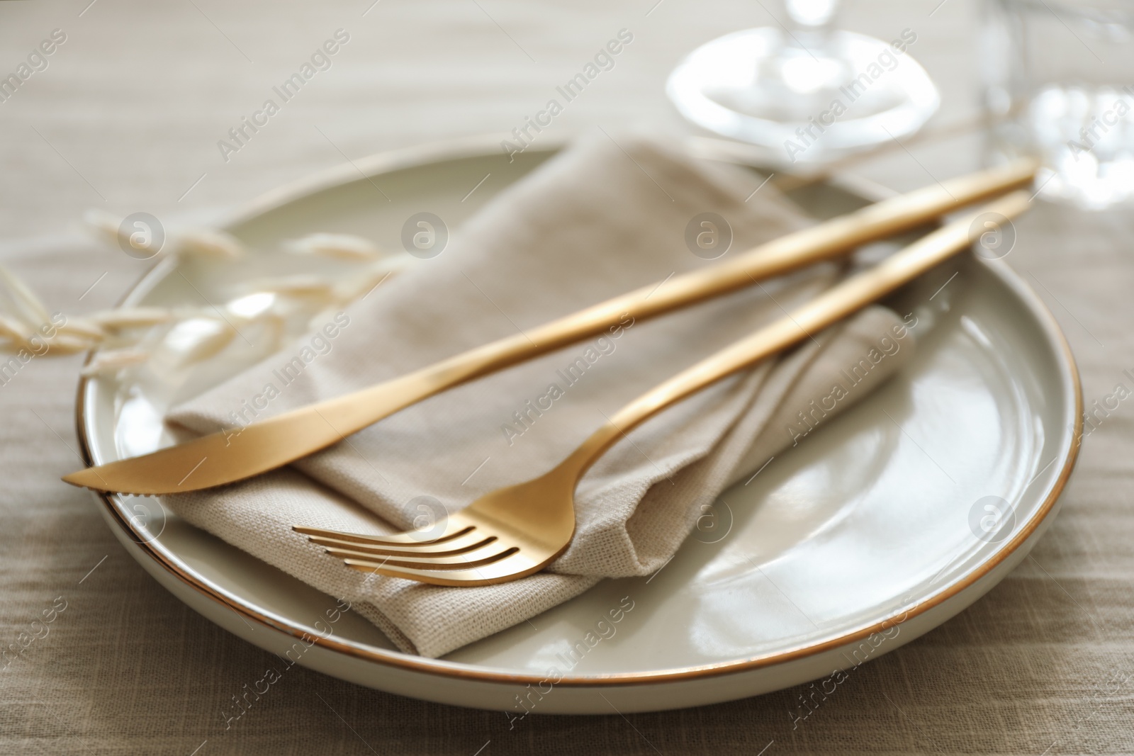 Photo of Stylish setting with cutlery, napkin and plate on light table, closeup