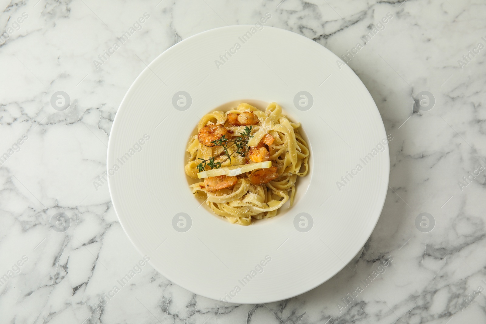 Photo of Delicious pasta with shrimps on white marble table, top view