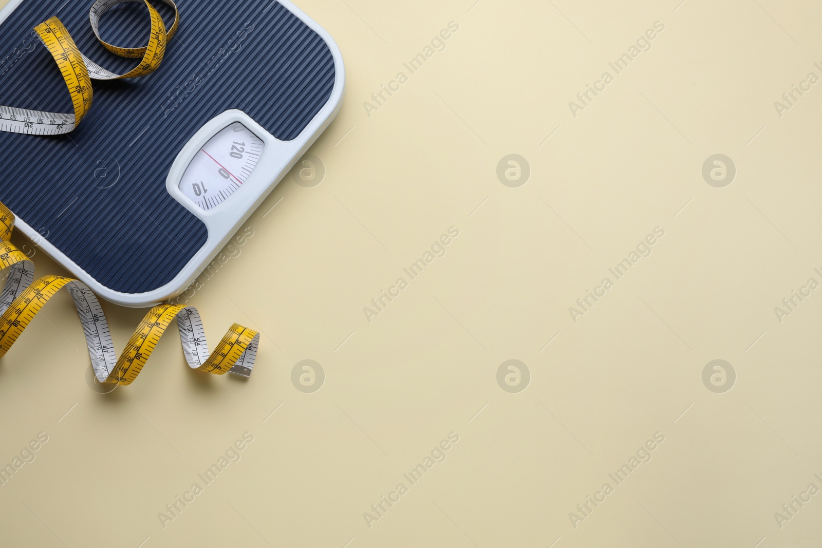 Photo of Scales and measuring tape on beige background, flat lay. Space for text