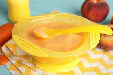 Baby food in bowl and fresh ingredients on table, closeup