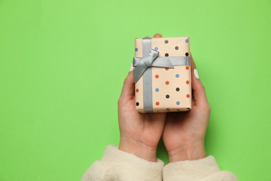 Woman with Christmas gift on green background, closeup. Space for text