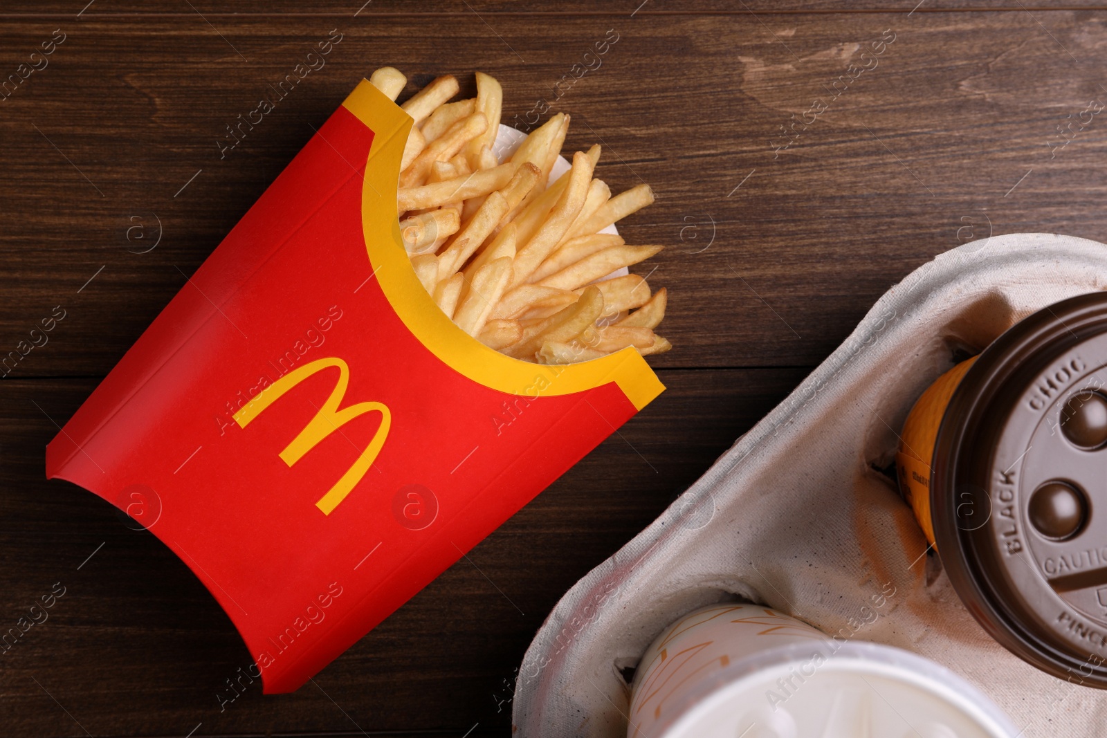 Photo of MYKOLAIV, UKRAINE - AUGUST 12, 2021: Big portion of McDonald's French fries and drinks on wooden table, flat lay