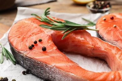 Fresh salmon steaks with spices and rosemary on table, closeup view