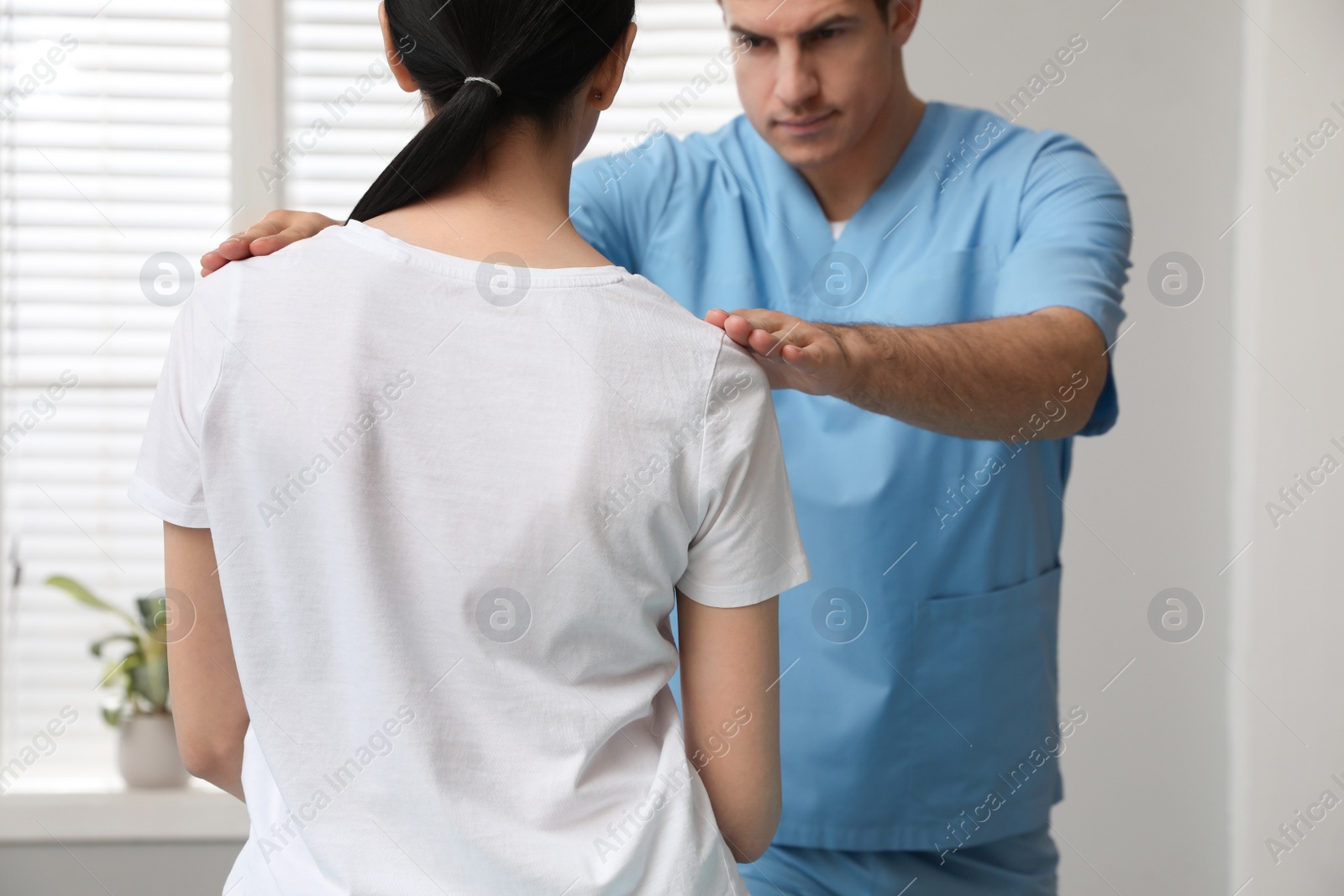 Photo of Orthopedist examining woman in clinic. Scoliosis treatment