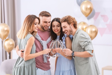 Happy friends with champagne in glasses at home