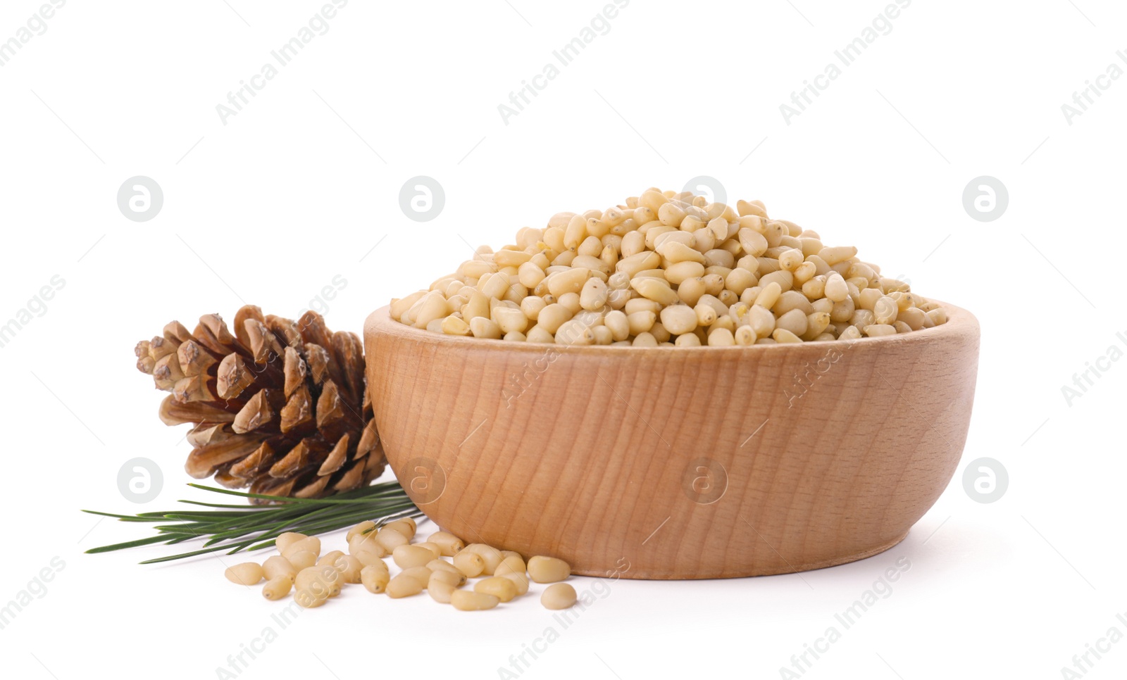 Photo of Bowl with pine nuts and cone on white background