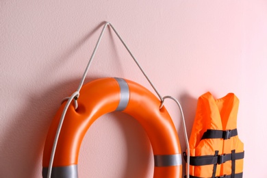 Photo of Orange life jacket and lifebuoy on pink background. Rescue equipment