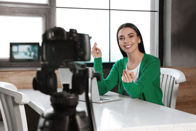 Photo of Young blogger with laptop recording video on camera at cafe