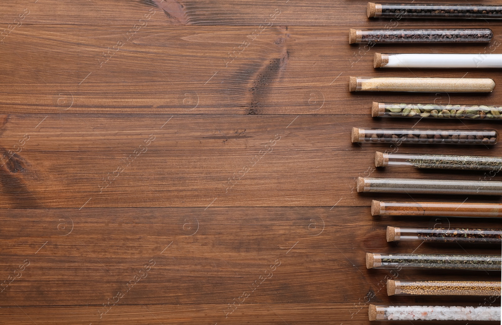 Photo of Test tubes with various spices on wooden table, flat lay. Space for text