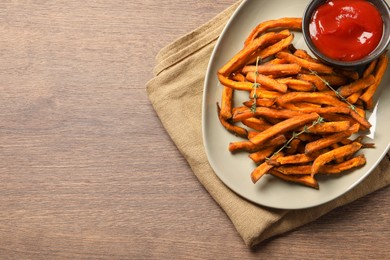 Sweet tasty potato fries and ketchup served on wooden table, top view. Space for text