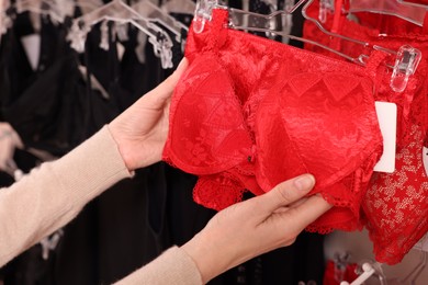Photo of Woman choosing bra in lingerie store, closeup