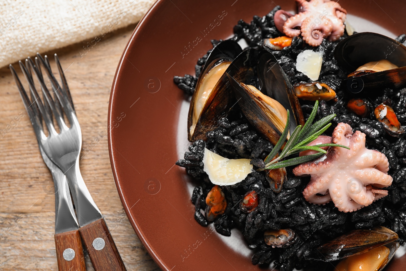 Photo of Delicious black risotto with seafood on wooden table, closeup