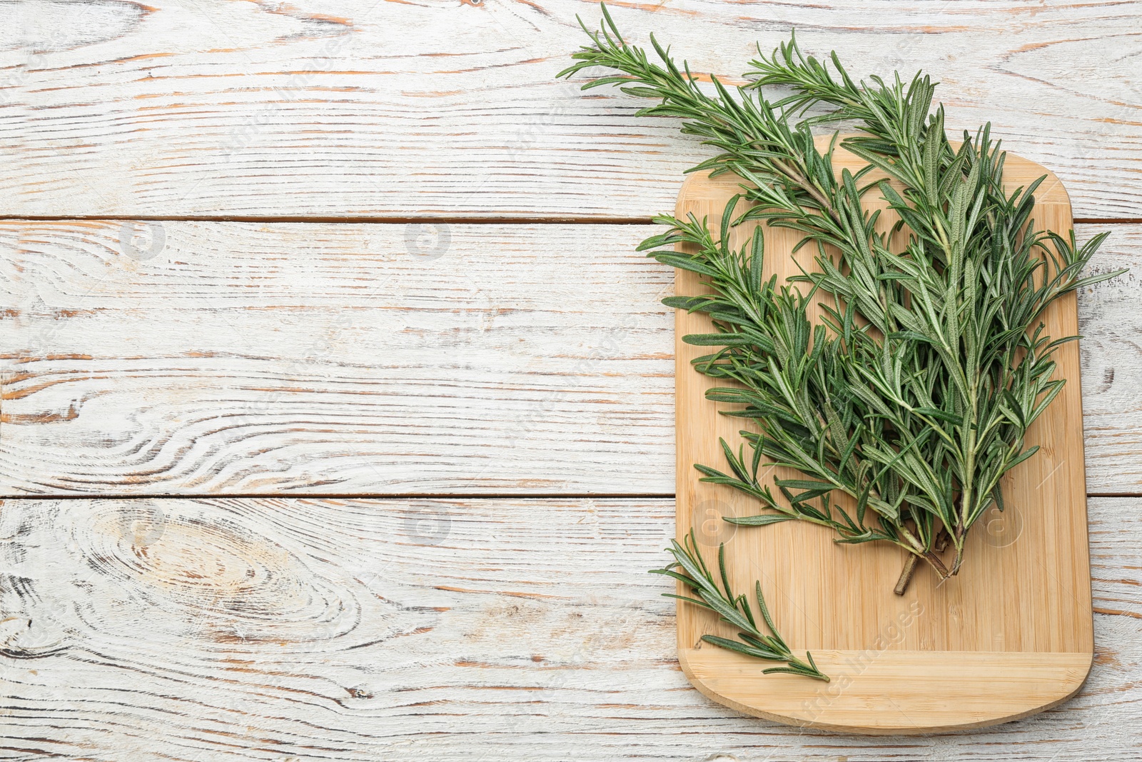 Photo of Bunch of fresh rosemary on white wooden table, above view. Space for text