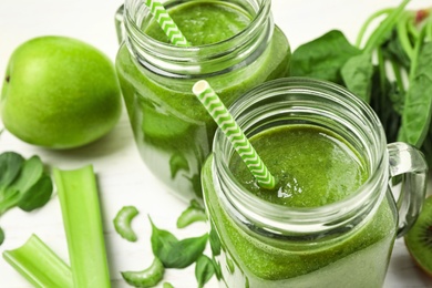 Photo of Delicious fresh green juice in mason jar on white table, closeup. Space for text