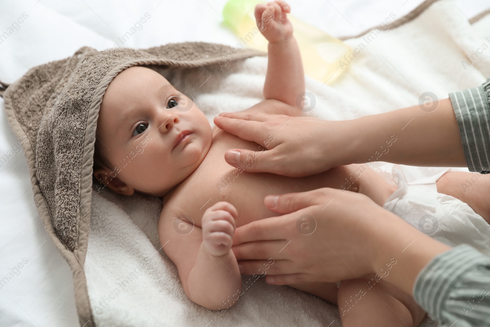 Photo of Mother massaging her cute baby with oil, closeup