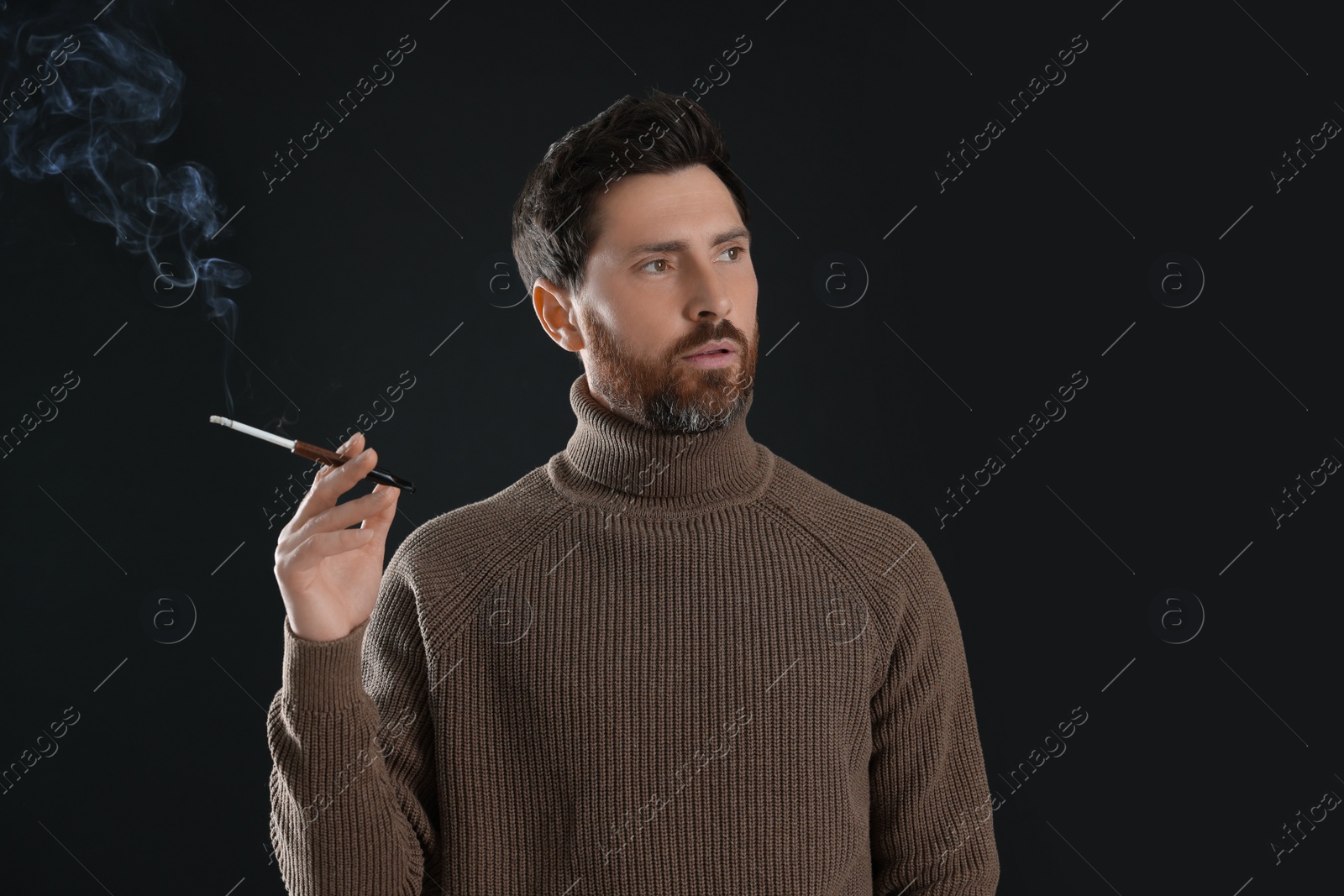 Photo of Man using cigarette holder for smoking on black background, space for text