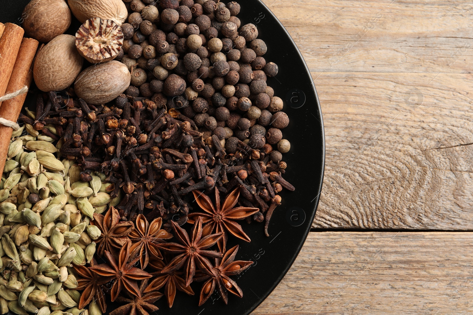 Photo of Different spices and nuts on wooden table, top view. Space for text