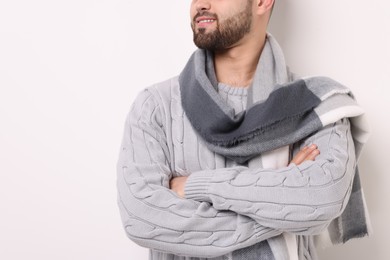Photo of Smiling man in warm scarf on light background, closeup. Space for text