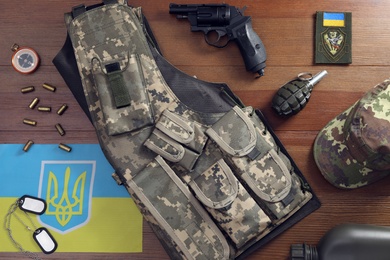 Photo of MYKOLAIV, UKRAINE - SEPTEMBER 26, 2020: Tactical gear and Ukrainian flag on table, flat lay
