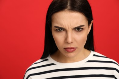 Photo of Angry young woman on red background. Hate concept