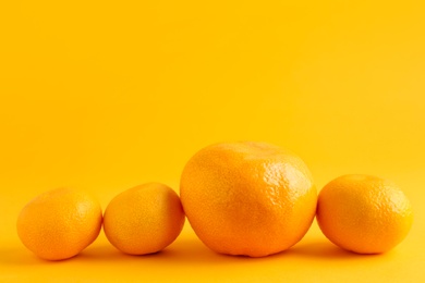 Photo of Ripe delicious tangerines and one bigger than others on orange background. Space for text