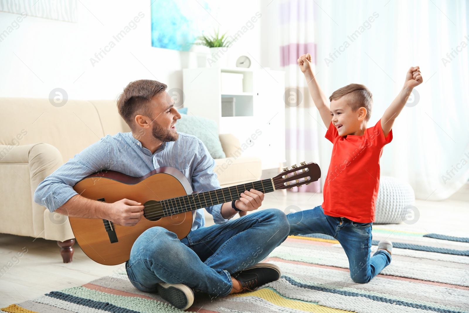 Photo of Father playing guitar for his son at home