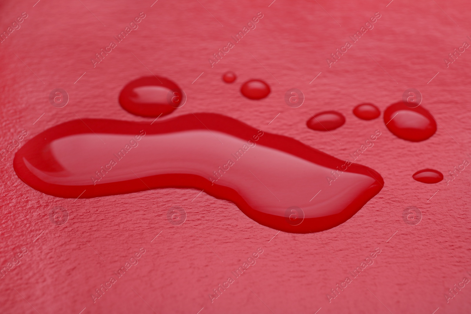 Photo of Puddle of water on red background, closeup