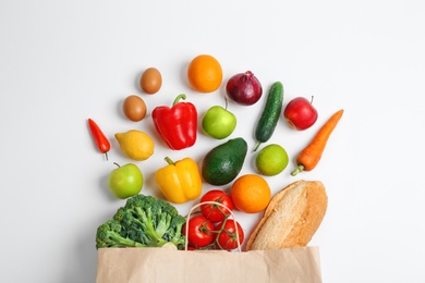 Photo of Paper bag with different groceries on white background, top view