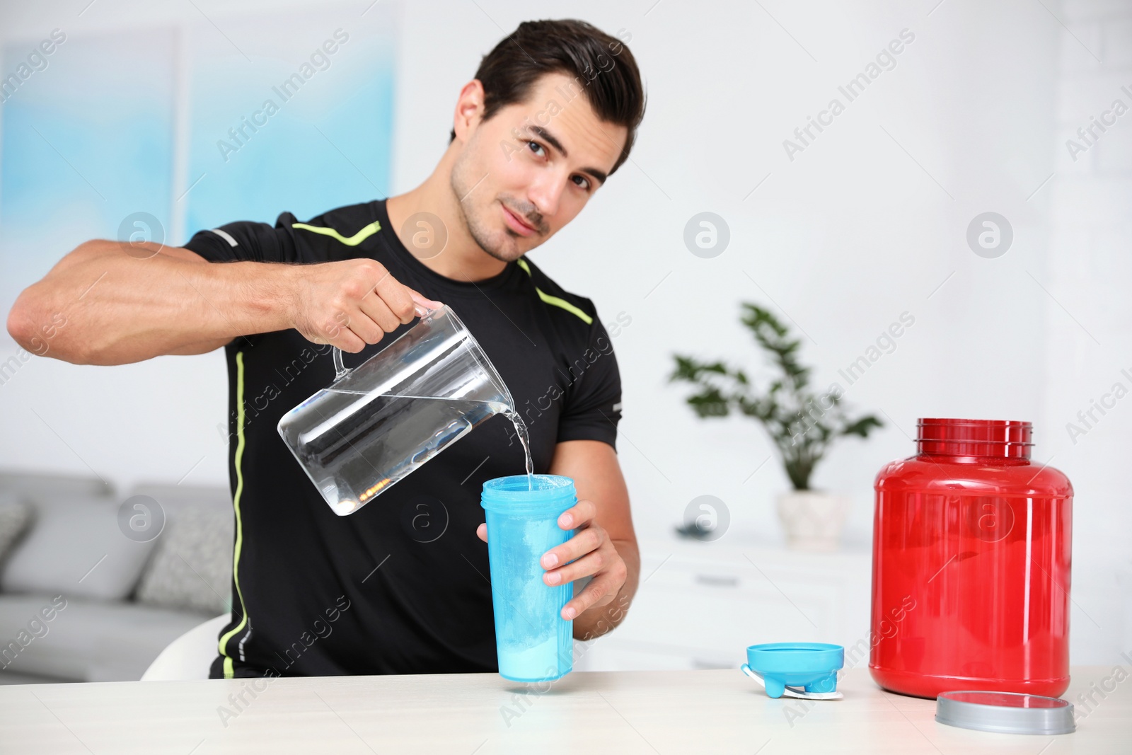 Photo of Young athletic man preparing protein shake at home