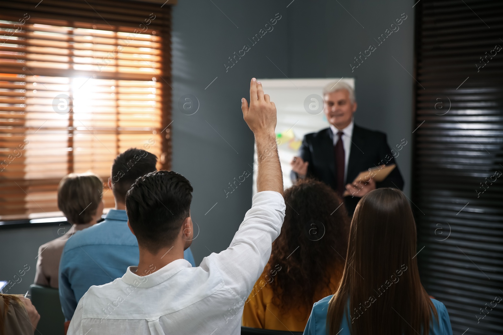 Photo of People raising hands to ask questions at seminar in office