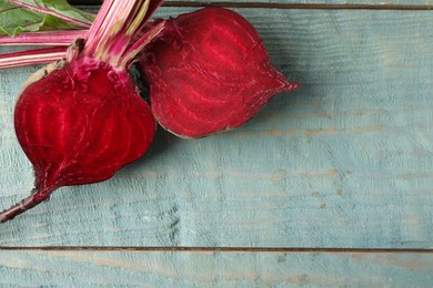 Photo of Halves of raw beet on blue wooden table, flat lay. Space for text