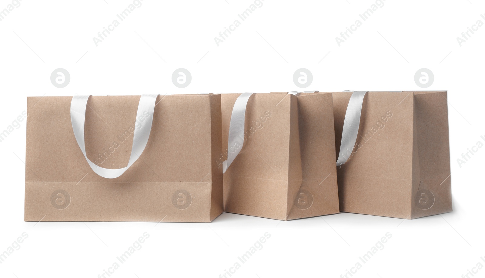 Photo of Paper shopping bags with ribbon handles on white background. Mockup for design