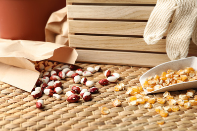 Photo of Different vegetable seeds and wooden crate on table, closeup