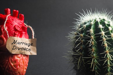 Photo of Model of heart with card Marriage Divorce and cactus on grey background, closeup. Space for text