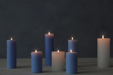 Photo of Burning candles on table against color wall