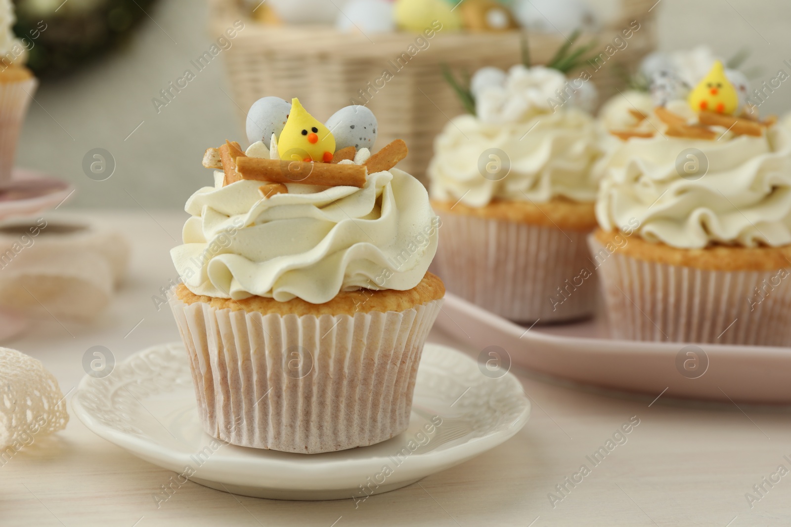 Photo of Tasty Easter cupcakes with vanilla cream on light wooden table